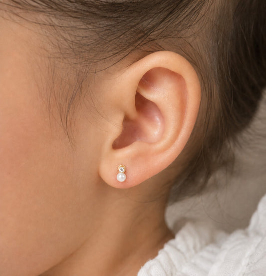 Close-up of an ear wearing a pearl earring with a neutral background
