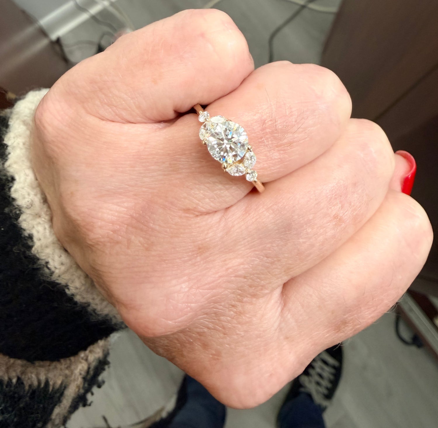 Hand wearing a diamond engagement ring with a blurred background