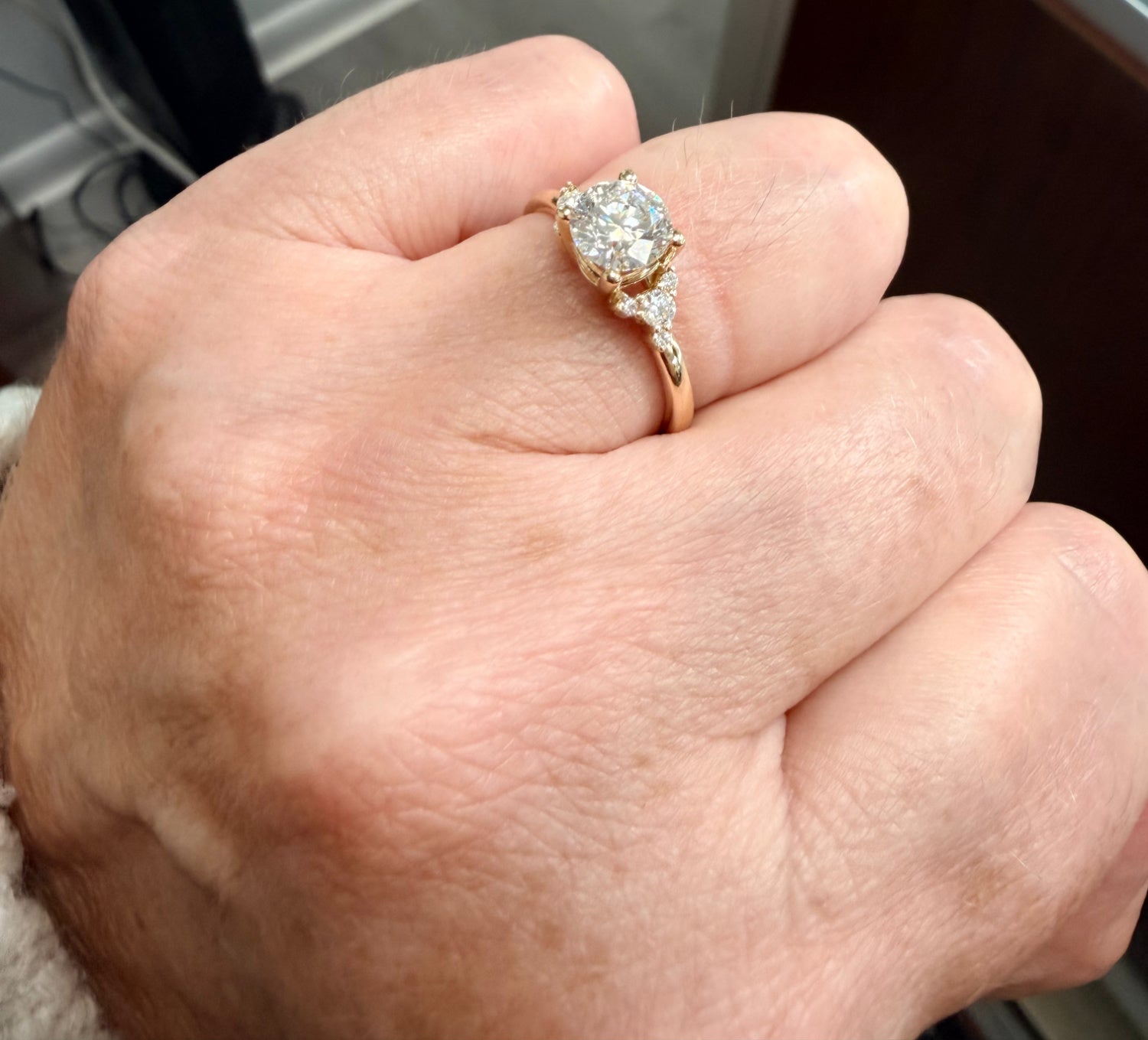 Angled view of a Hand wearing a diamond engagement ring with a blurred background
