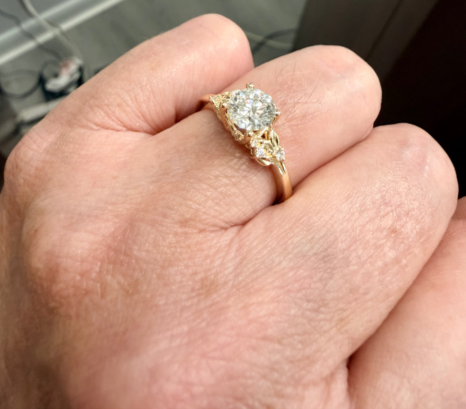 Gold engagement ring with a round diamond on a person's finger