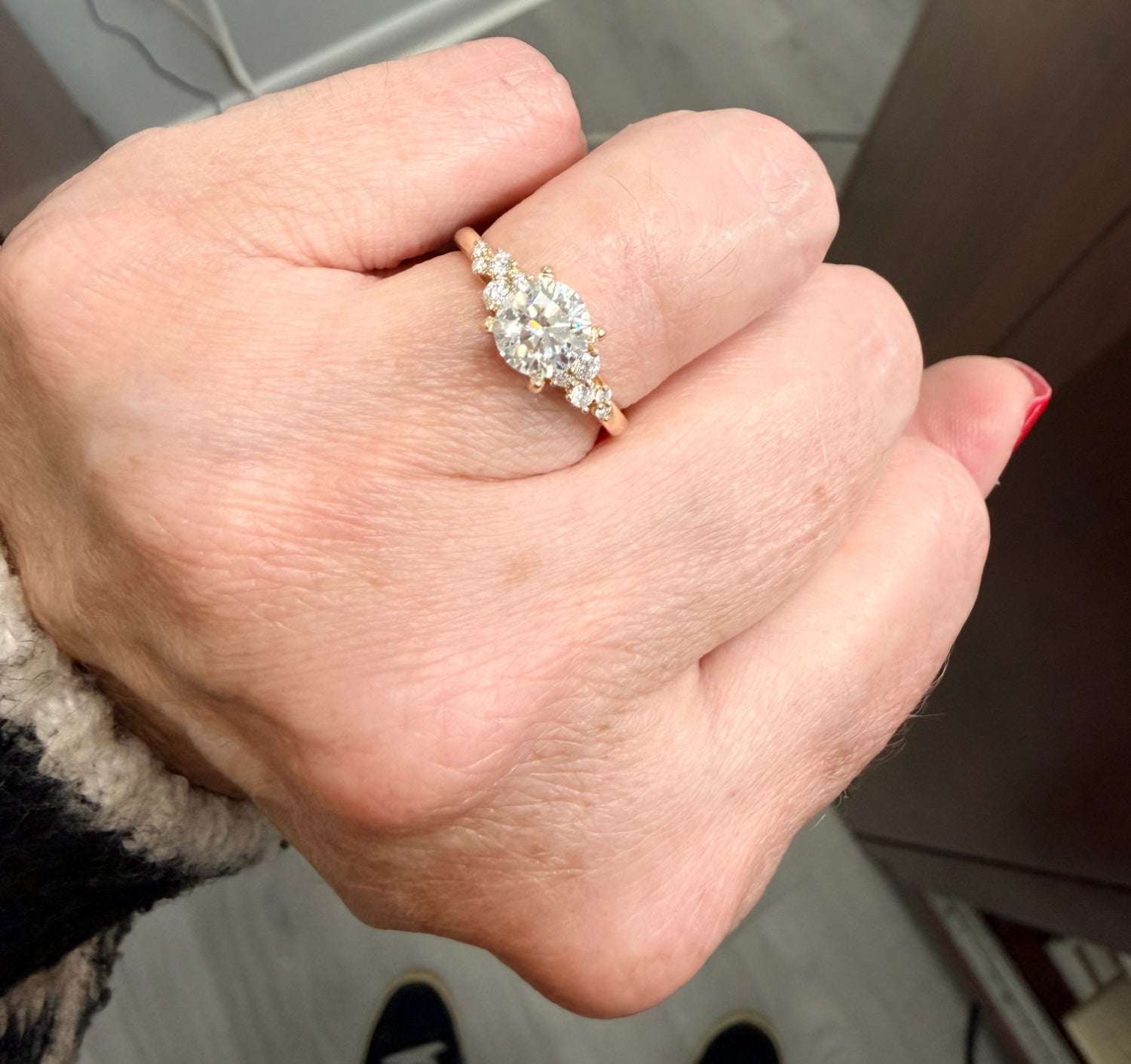 Hand wearing a diamond engagement ring with a blurred background