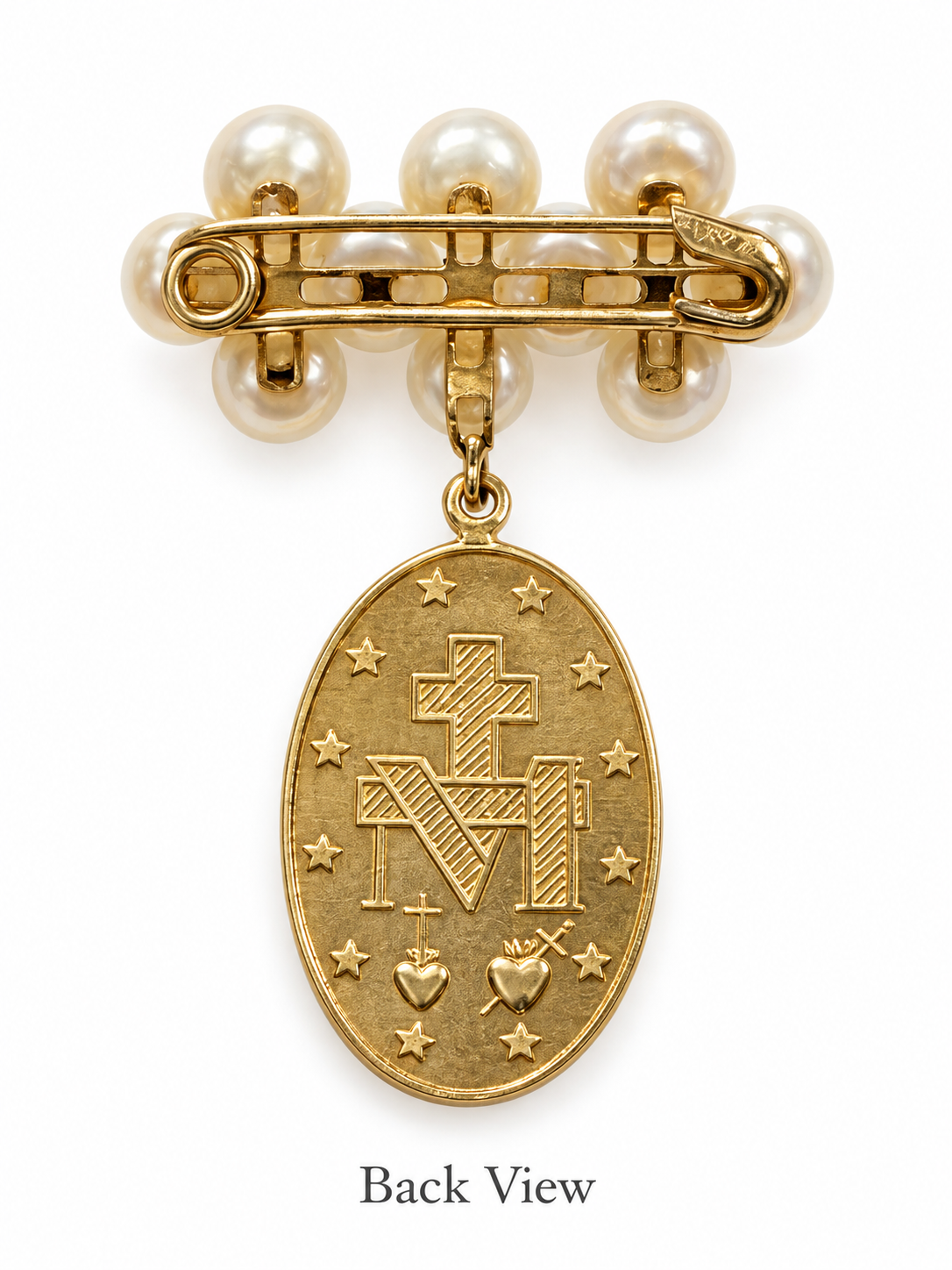 Gold and pearl religious brooch showing the back view  an oval Miraculous Medal pendant featuring a cross and monogram, attached to a safety pin clasp with pearl-like beads on a white background.