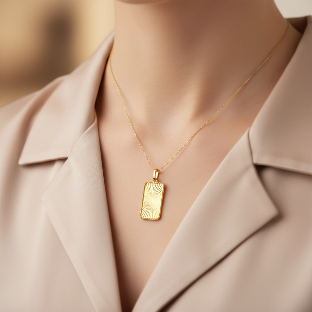 Woman wearing a beige coat with a gold  necklace featuring a rectangular fluted sunburst pendant.