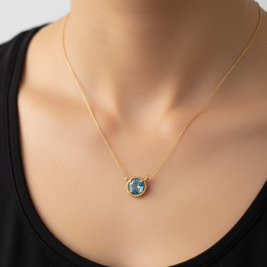 Gold necklace with a blue topaz gemstone pendant on a woman's neck