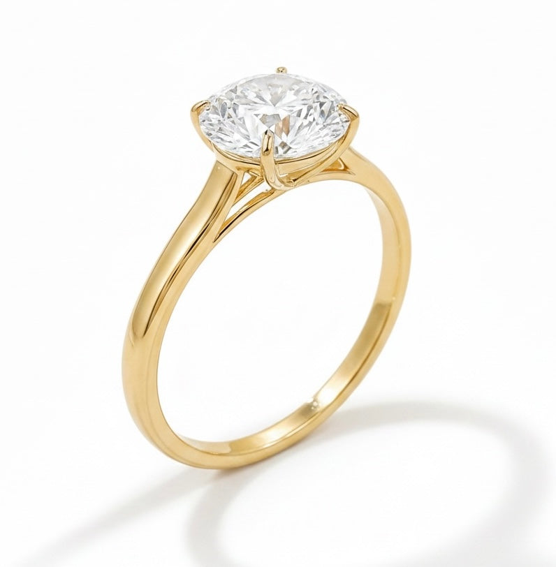 A yellow gold solitaire engagement ring with a round brilliant-cut diamond set in a four-prong cathedral setting, shown on a clean white background with a soft shadow.