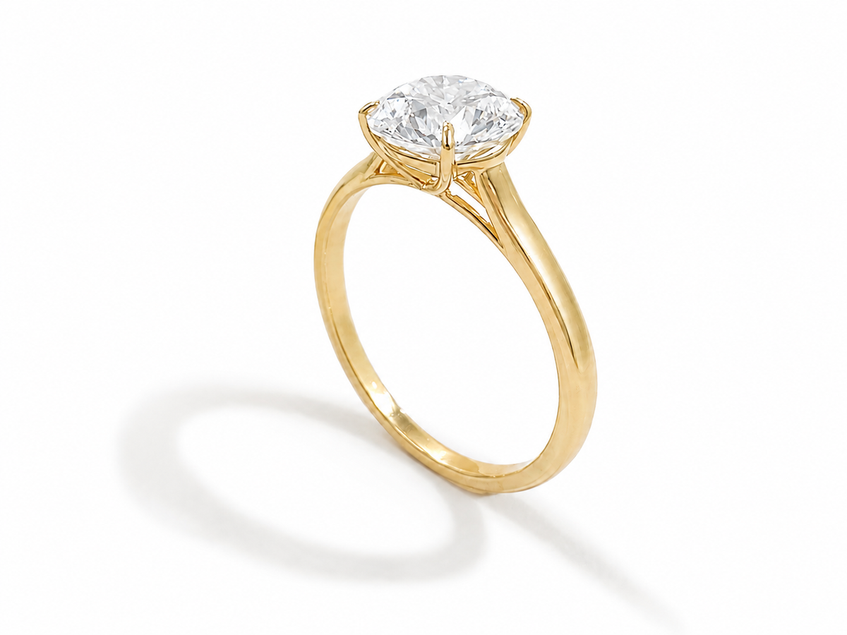 A yellow gold solitaire engagement ring featuring a round-cut diamond, set against a clean white background with a soft shadow.