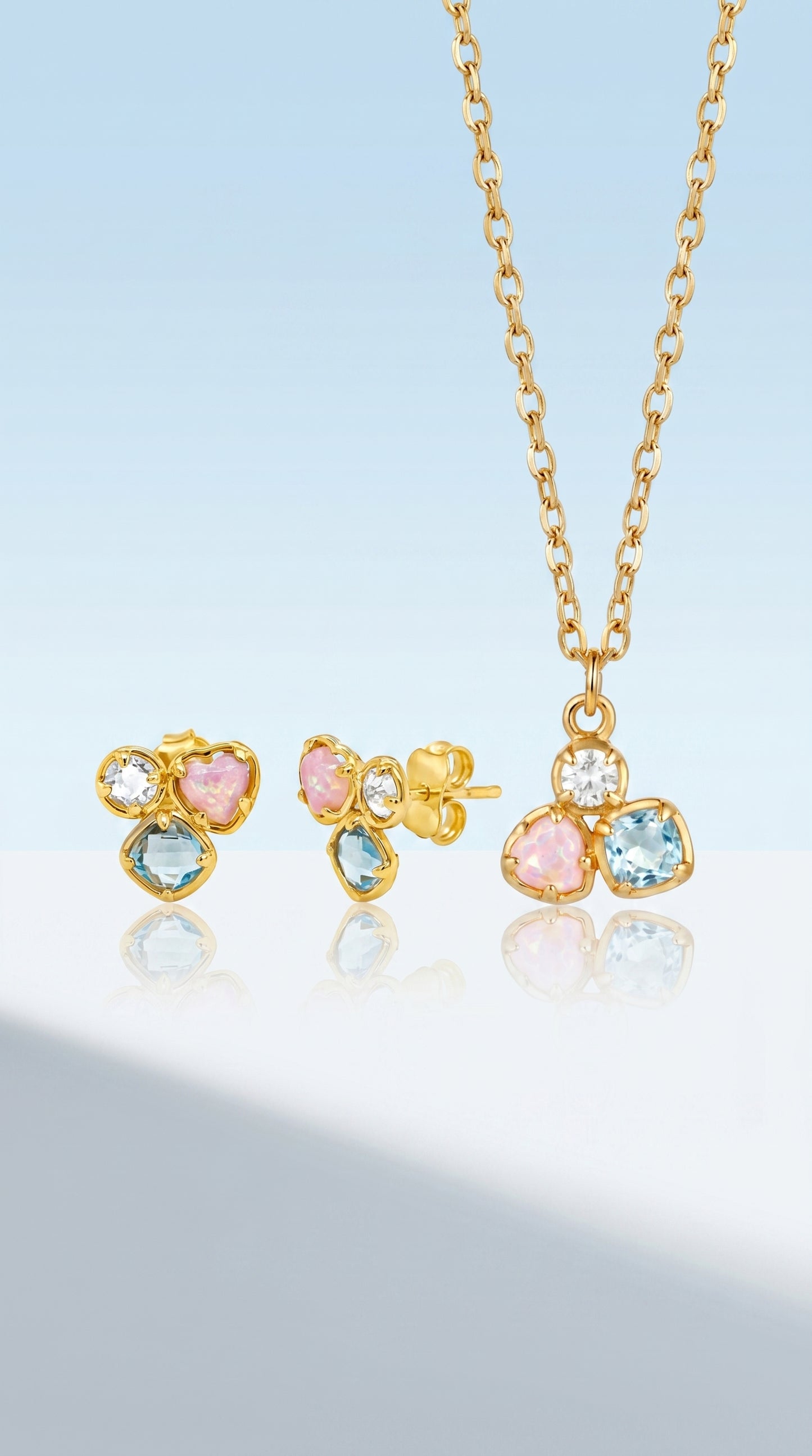 Gold jewelry set with earrings and a necklace on a light blue background