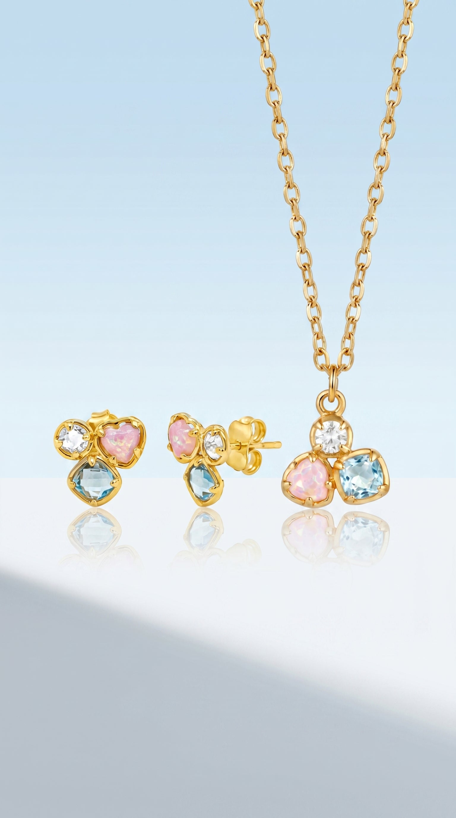 Gold jewelry set with earrings and a necklace on a light blue background