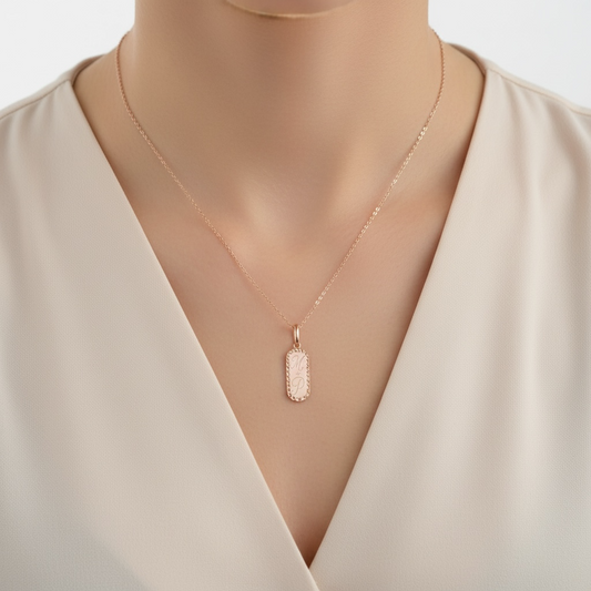 Necklace with a pendant on a woman's neck engraved with M + P wearing a beige top