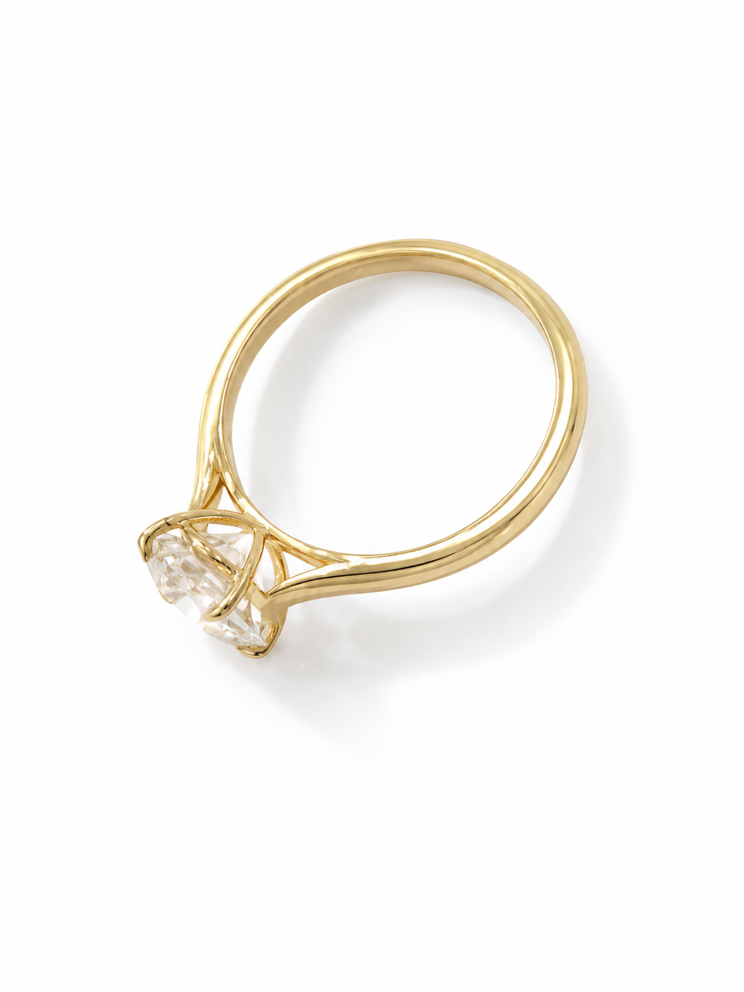 A yellow gold ring with a cathedral shank design and a clear, basket prong setting with a round diamond gemstone, photographed on a clean white background with a soft shadow.