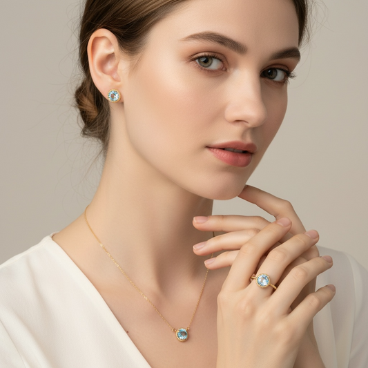 Woman wearing a necklace, ring, and earrings with blue topaz gemstones on a neutral background