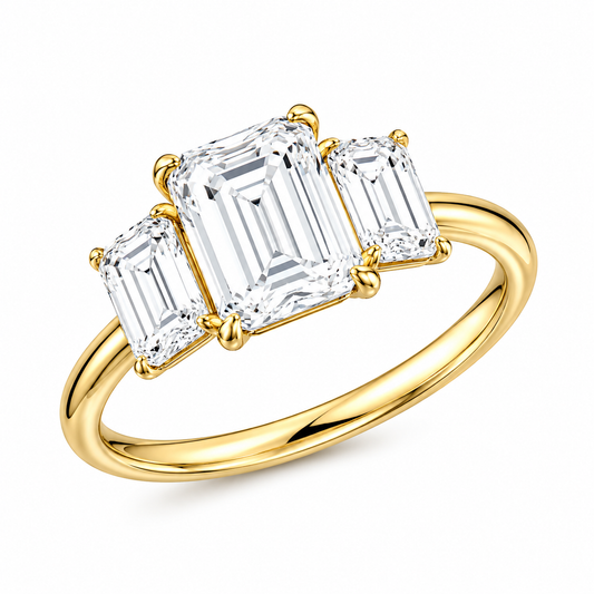 A yellow gold three-stone ring featuring a large emerald-cut center diamond flanked by two smaller emerald-cut diamonds, set against a clean white background.