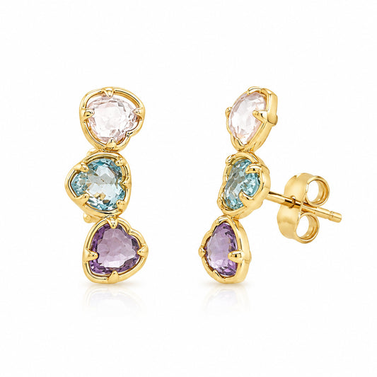 A pair of crawler/climber earrings featuring three heart-shaped gemstones in each earring: a pale pink top stone, a light blue middle stone, and a purple bottom stone. One earring is shown from the front and the other from the side/back, on a clean white background.