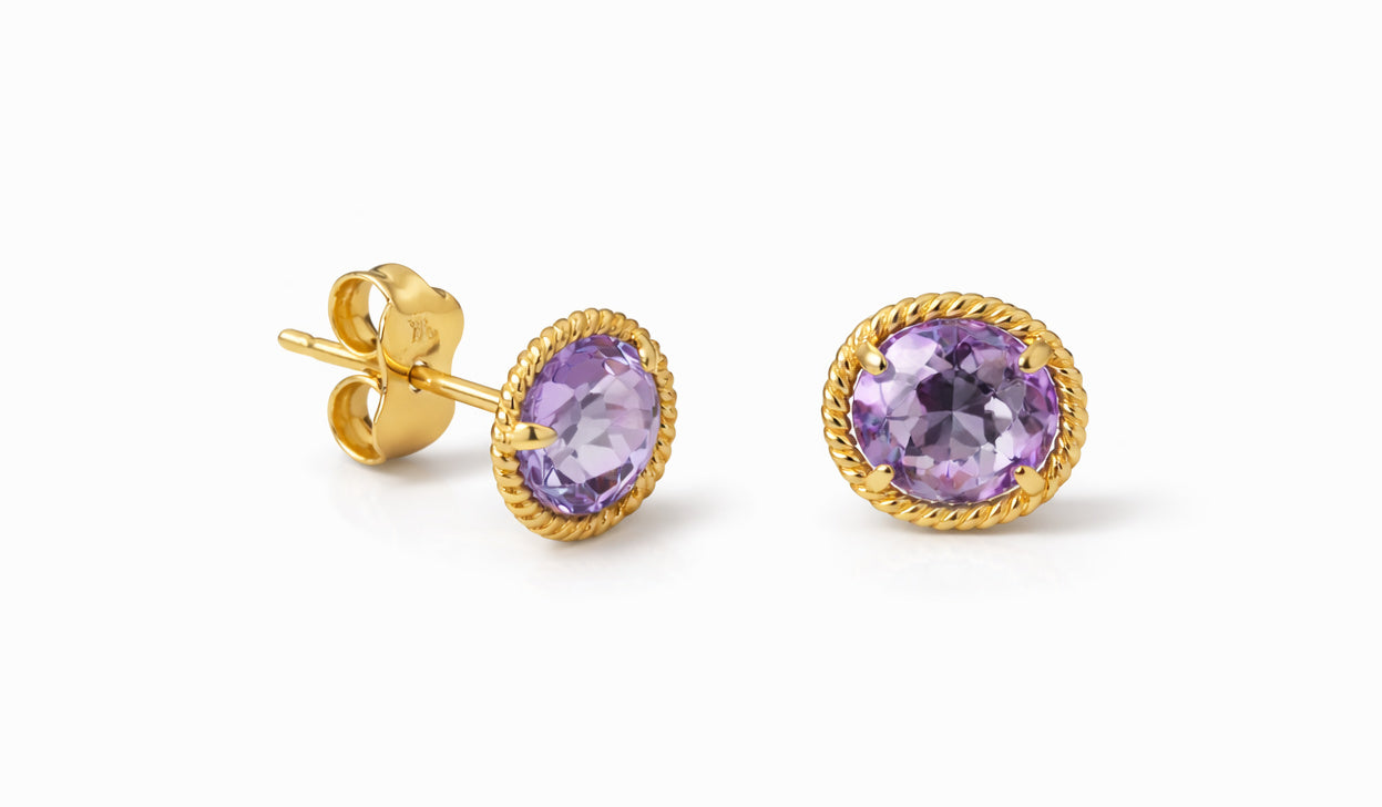 Gold earrings with purple amethyst gemstones on a white background