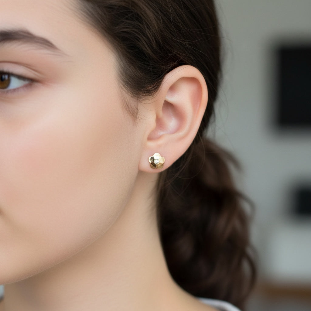 Close-up of a person wearing a gold flower-shape earring with a blurred background