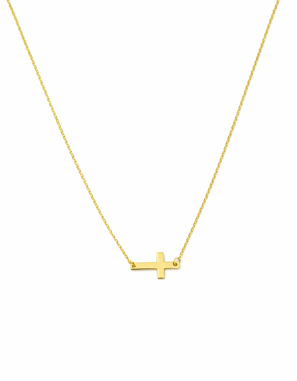 Gold necklace with a small sideways cross pendant on a white background