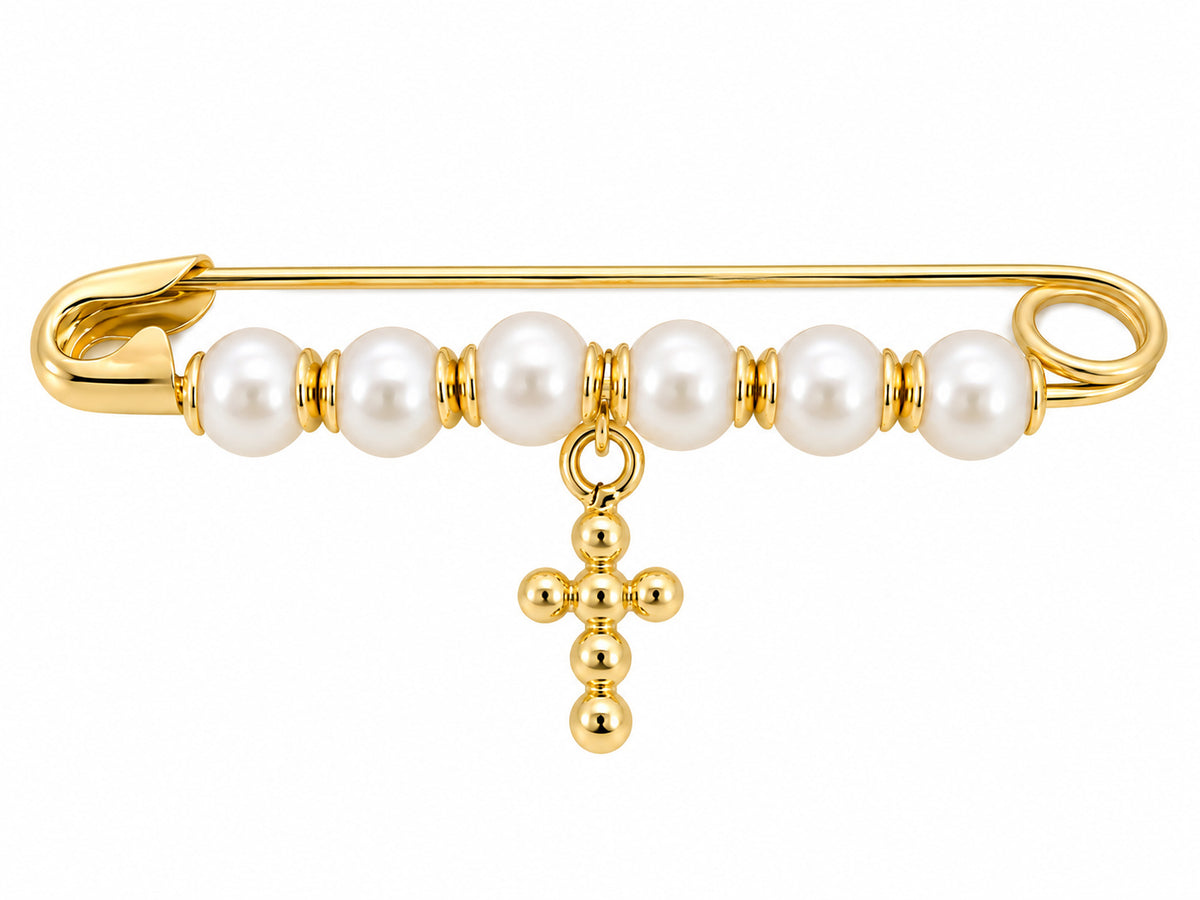 A gold safety pin brooch decorated with white fresh water pearls and a dangling gold cross charm, shown on a plain white background.
