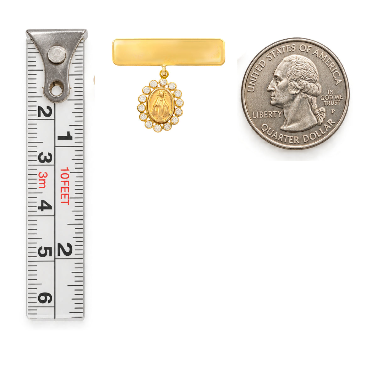A 14K gold engravable bar baby pin with a small oval religious Miraculous medallion and a halo of cubic zirconia stones, shown next to a metal tape measure and a U.S. quarter coin.