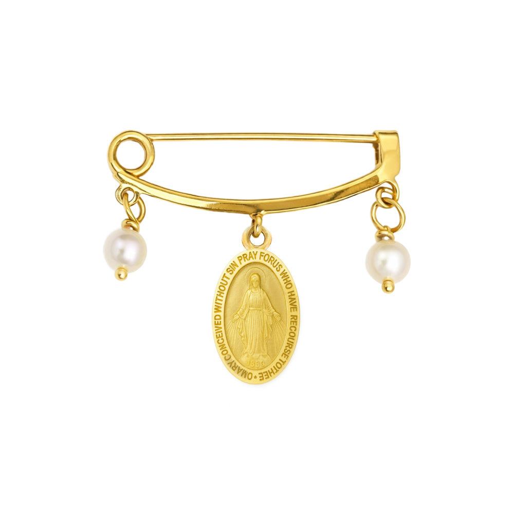 Gold safety pin brooch featuring a Miraculous Medal charm and two dangling white pearl beads, shown on a plain white background.