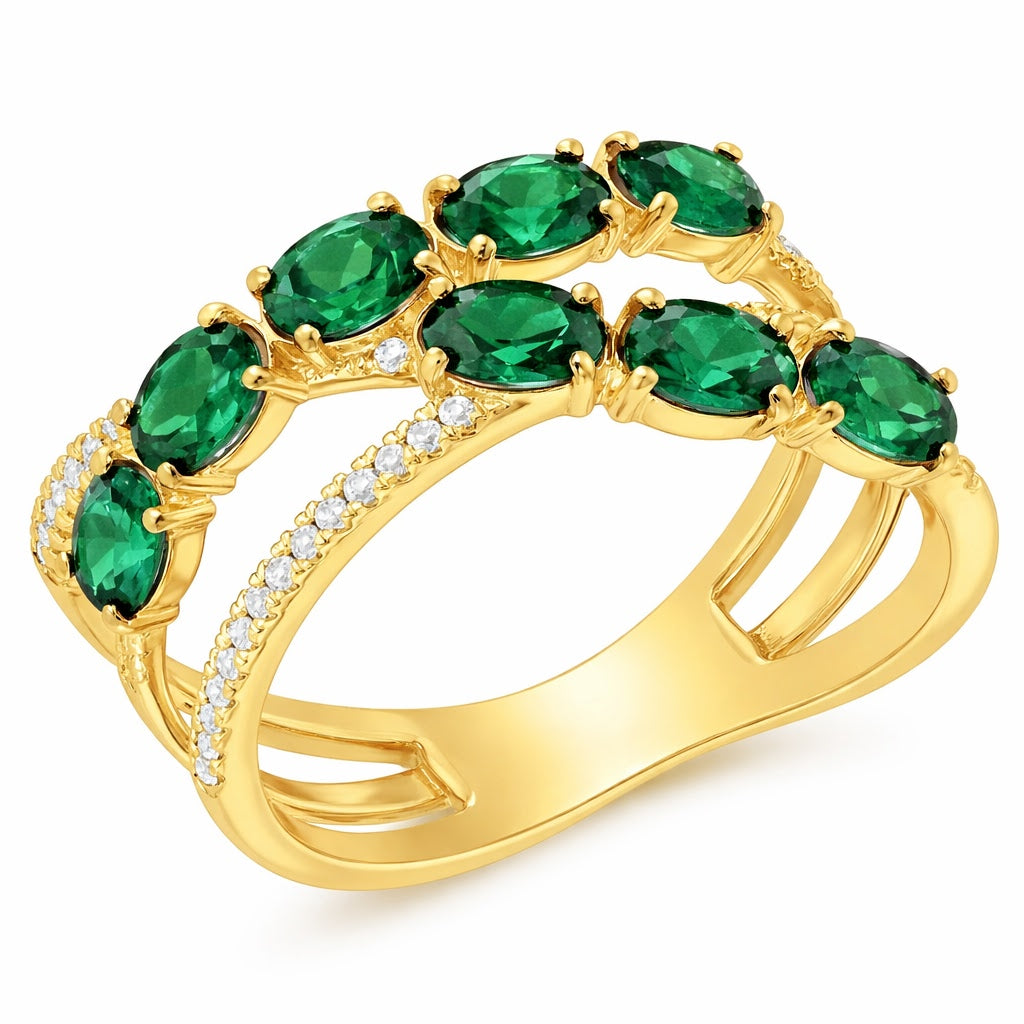 Gold ring with emerald green gemstones on a white background