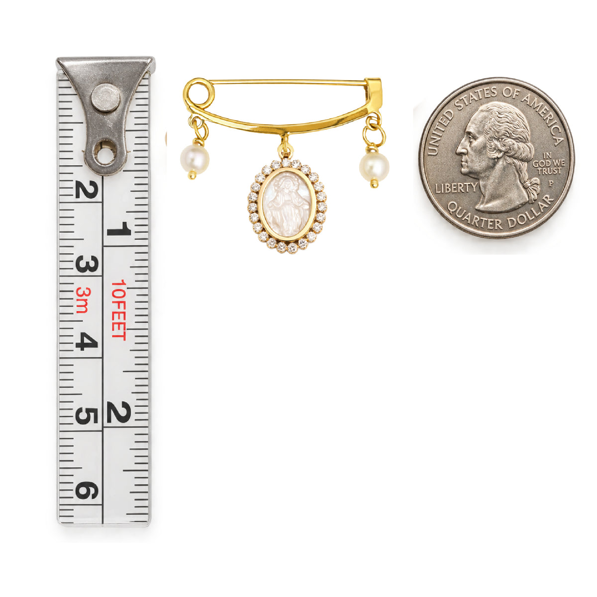 A 14K gold brooch with hanging pearl and an oval mother of pearl Miraculous  Medal pendant and two small pearl drops, shown next to a metal ruler for scale and a U.S.