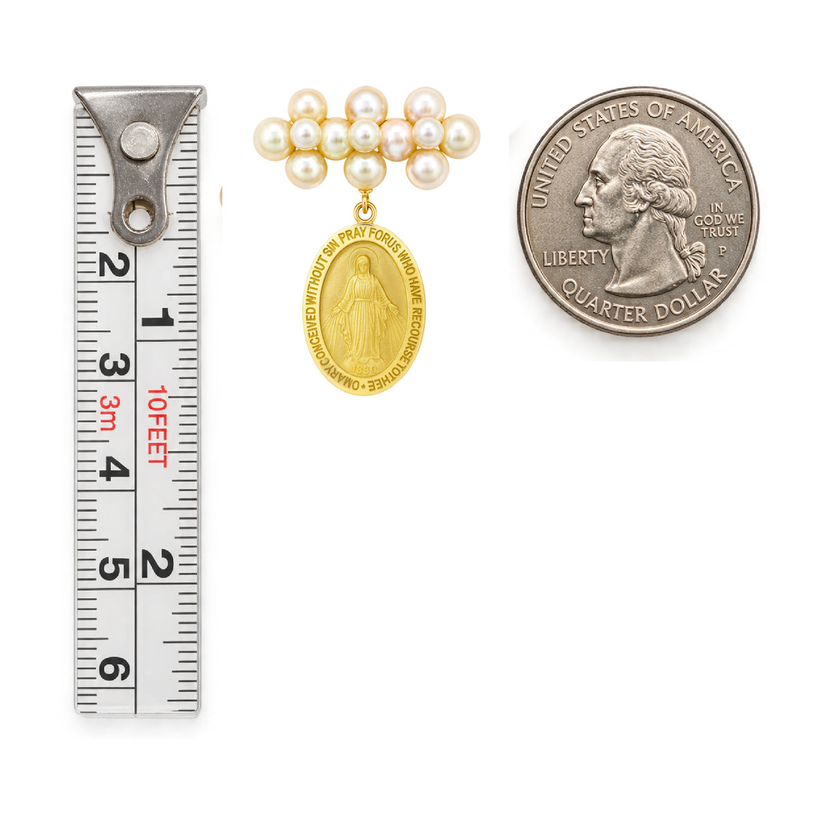 A gold and pearl Miraculous Medal religious pendant set shown with a metal ruler and a US quarter coin for scale, on a plain white background.