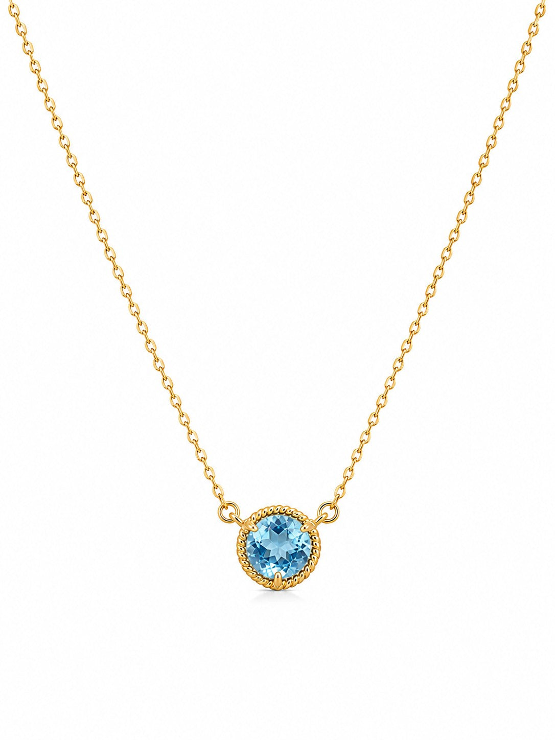Gold necklace with a blue topaz gemstone pendant on a white background
