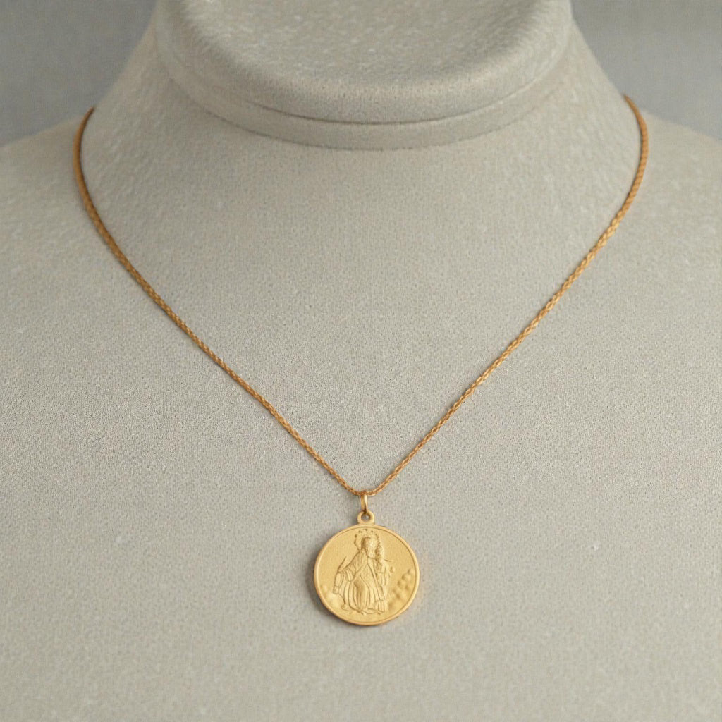 Gold necklace with a round medal of Our Lady of Mount Carmel pendant on a mannequin bust.