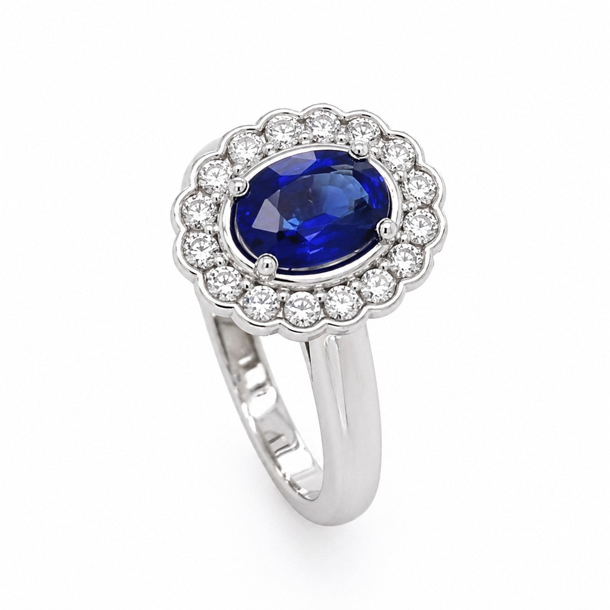 A 14K white gold ring with a central oval blue sapphire surrounded by a halo of smaller diamonds.