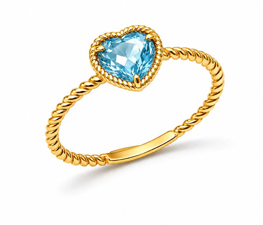 Gold ring with a heart-shaped blue topaz gemstone on a white background