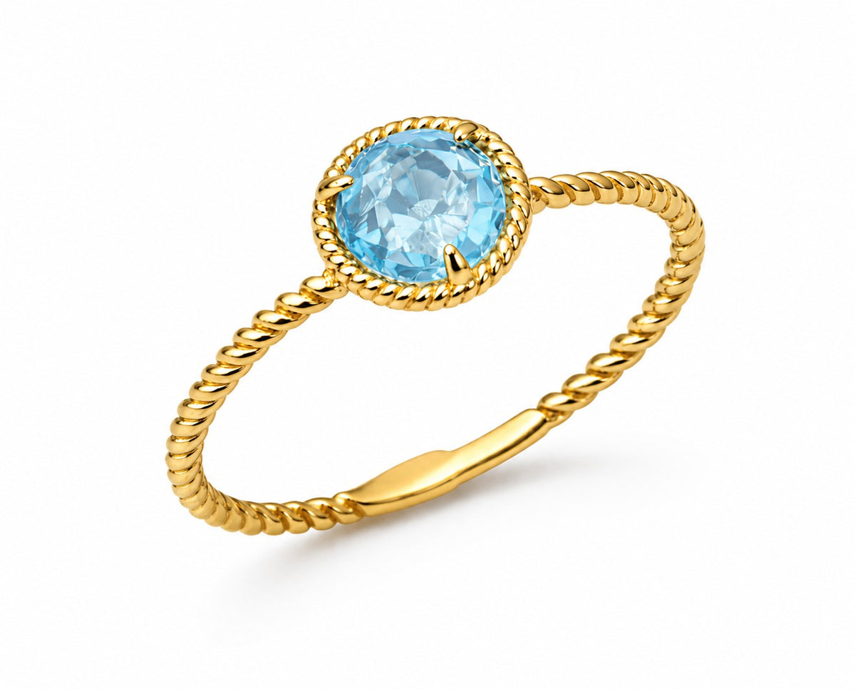 Gold ring with a blue topaz gemstone on a white background